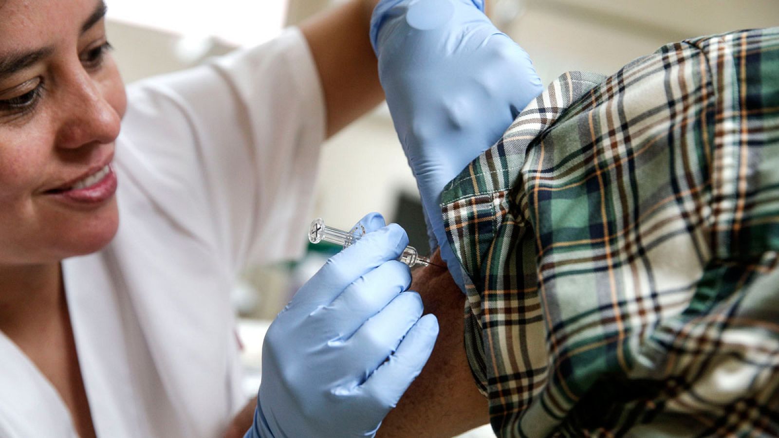 Una enfermera vacuna de la gripe a una paciente