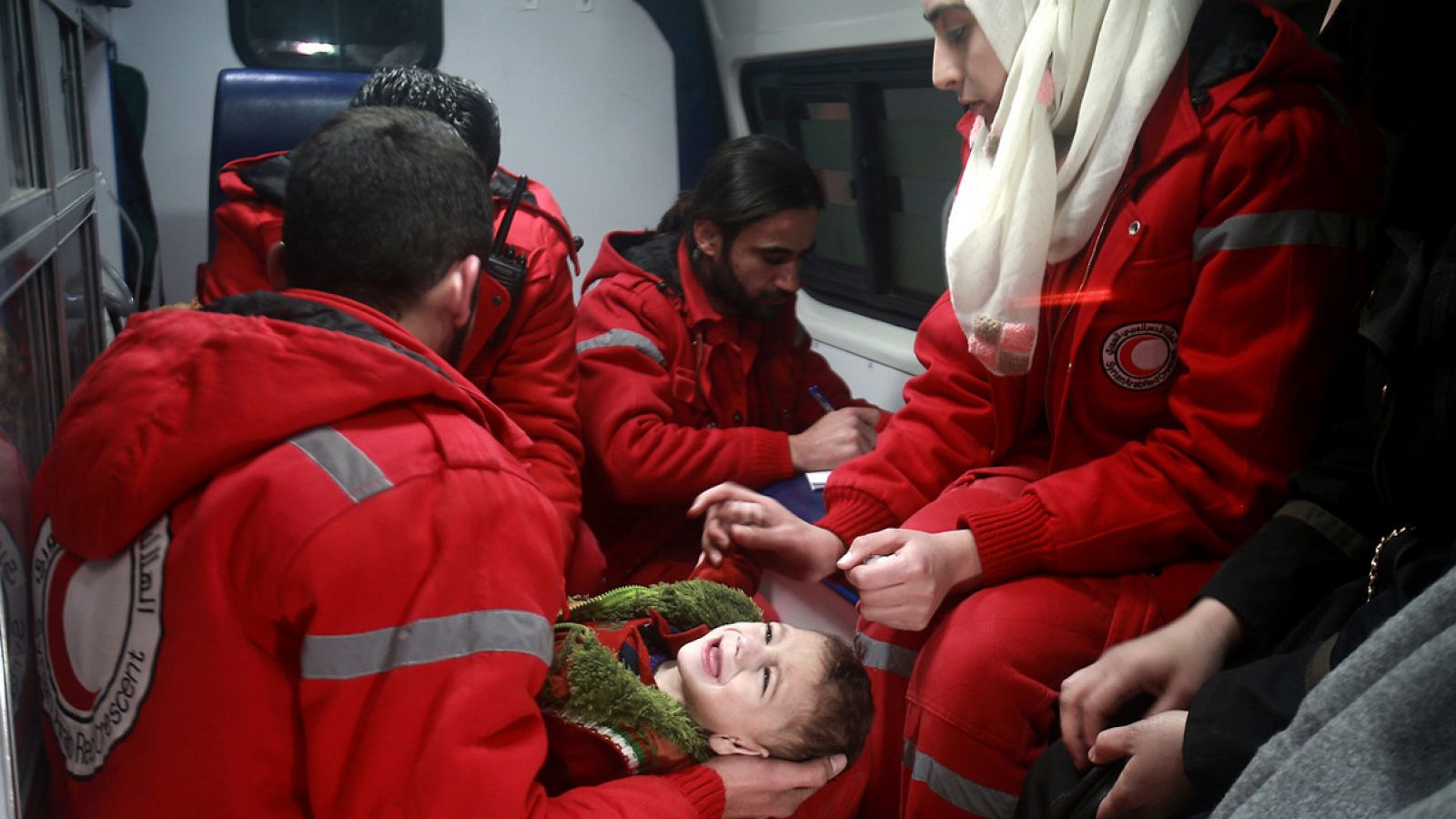 Personal de la Media Luna Roja evacúa a un niño de la región de Guta Oriental, en Siria