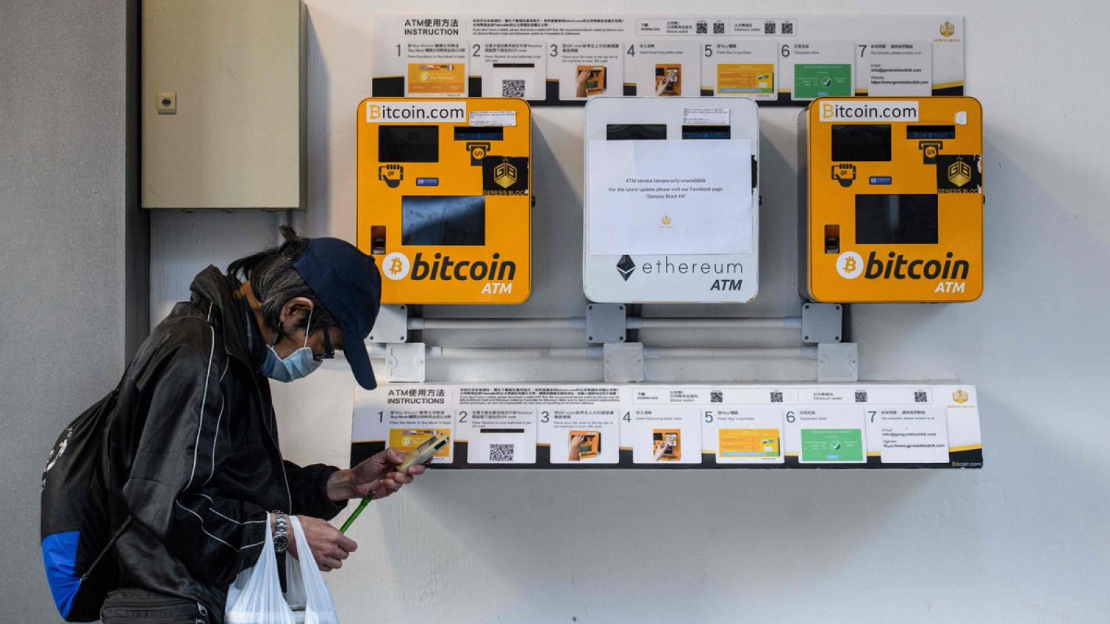 Un hombre consulta su móvil delante de unos cajeros automáticos especiales para bitcoins en la ciudad de Hong Kong