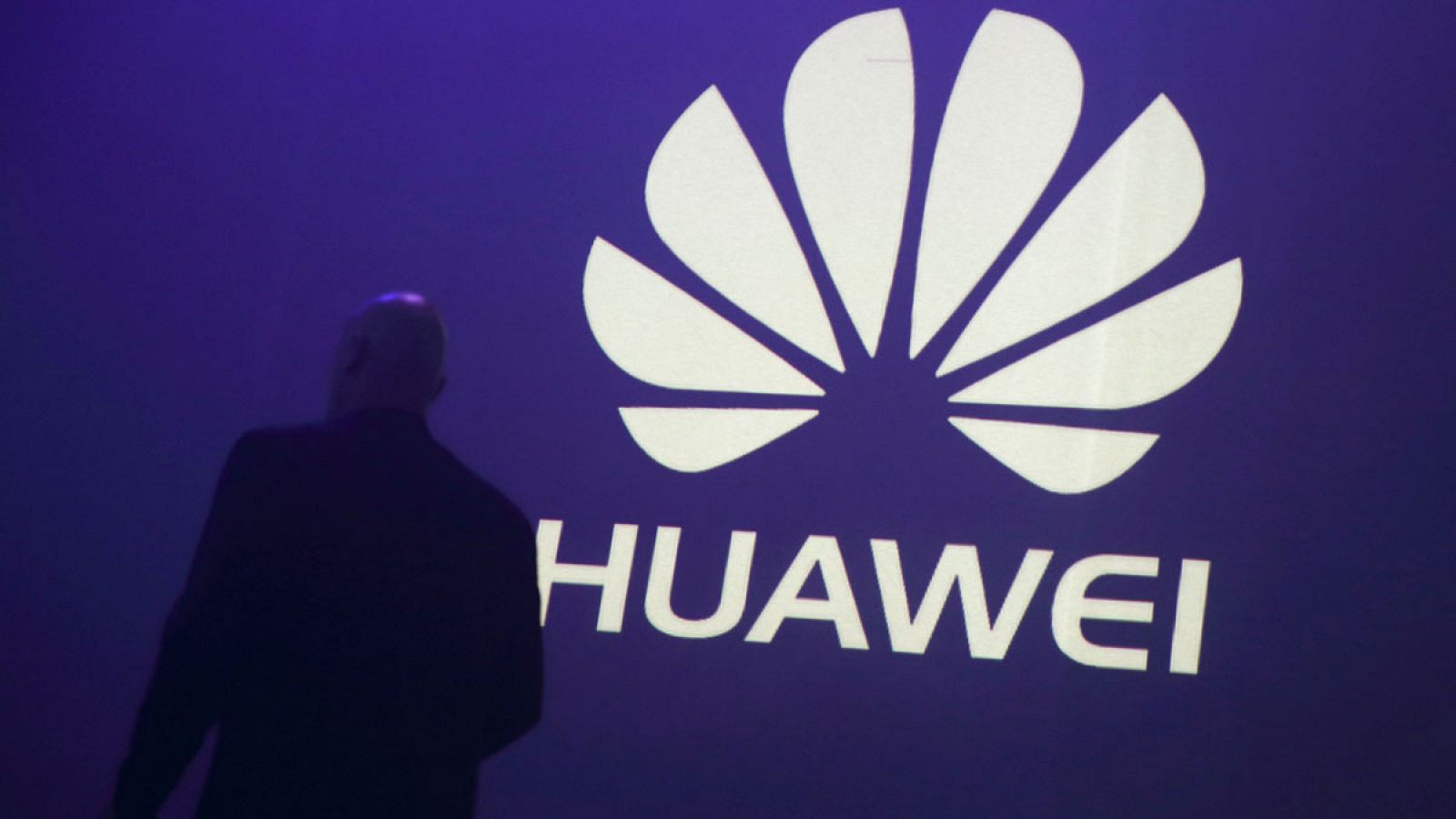 Un hombre pasa delante del logo de Huawei durante la presentación de un móvil de la empresa china