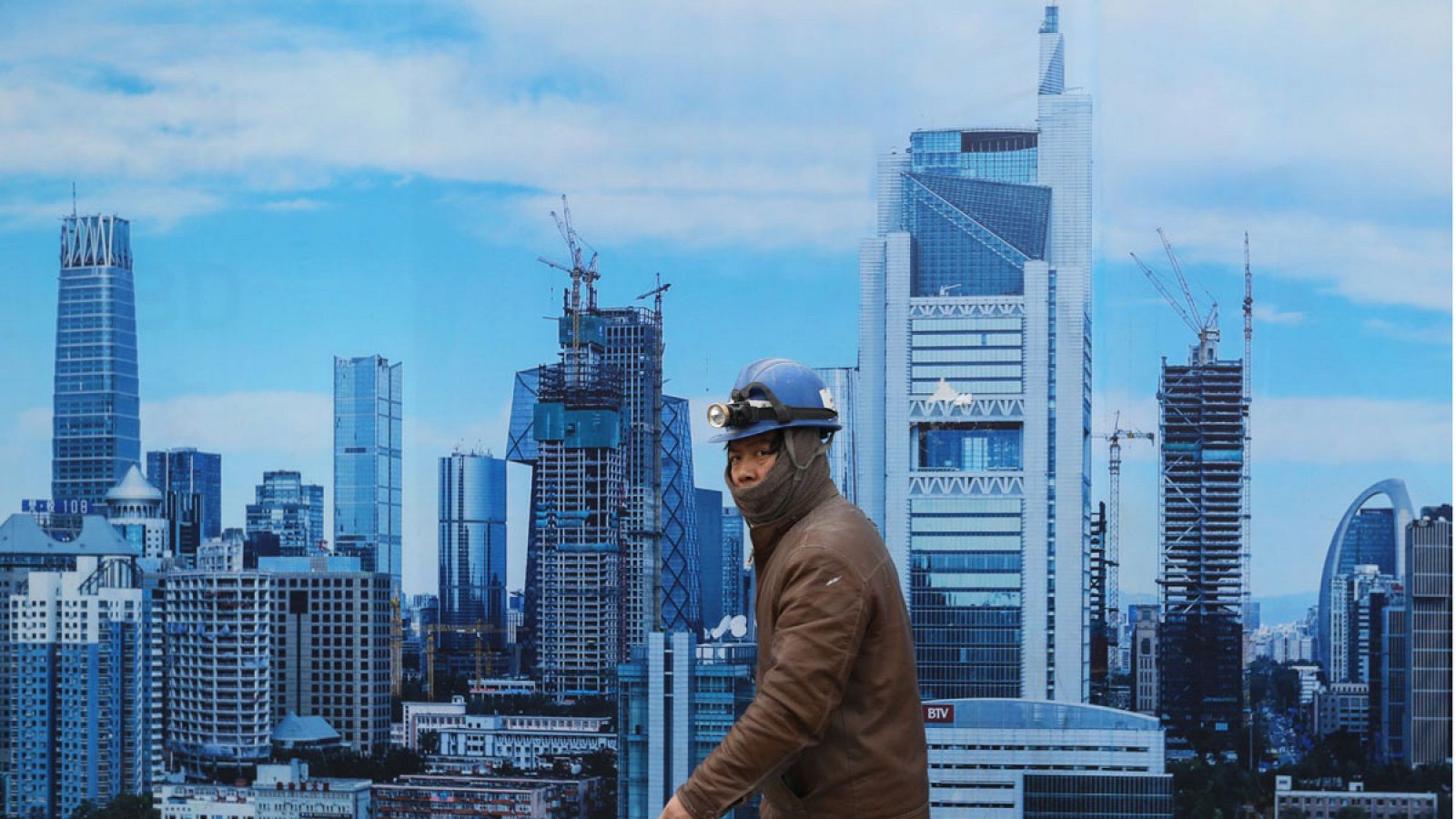 Un obrero camina junto a un cartel publicitario de una constructora en la capital de China, Pekín