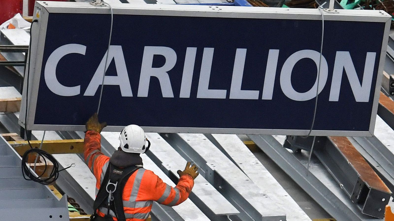 Un trabajador baja un cartel de Carillion de una grúa en unas obras en la City londinense