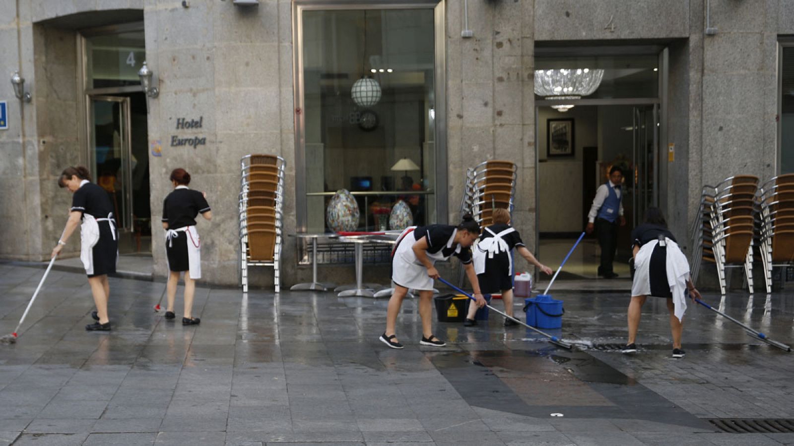 Un grupo de trabajadoras limpia la acera antes de montar la terraza de un hotel madrileño