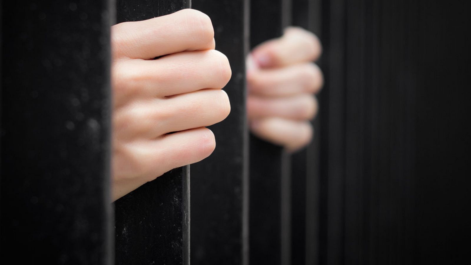 Las manos de un preso aprietan los barrotes de una celda