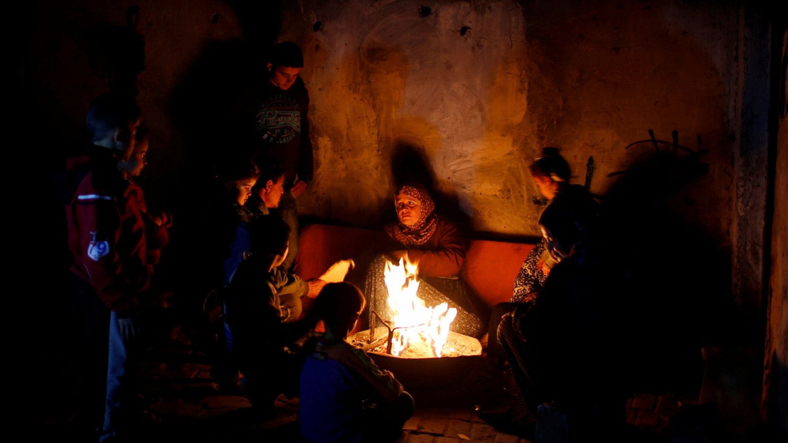 Una familia palestina se calienta en una hoguera en su casa en Gaza