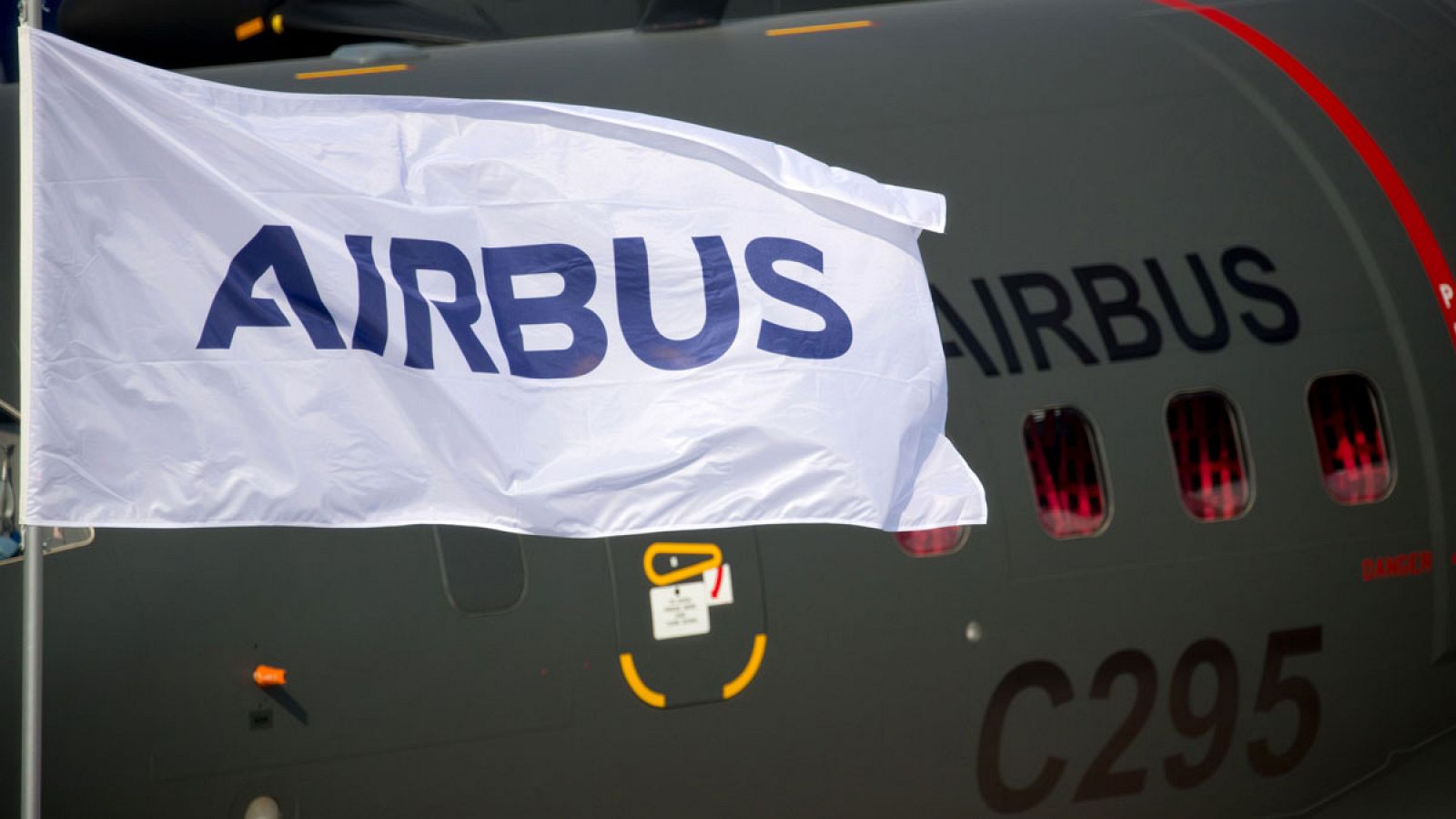 Una bandera con el logo de Airbus ondea delante de un avión militar C295