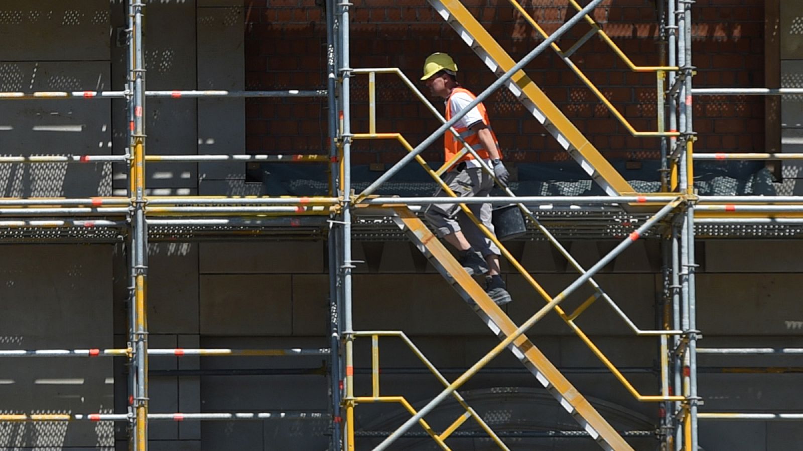 Un obrero sube por el andamio de un edificio en construcción en Berlín