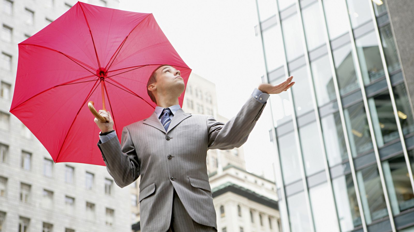 Un ejecutivo balancea un paraguas rojo sin que llueva