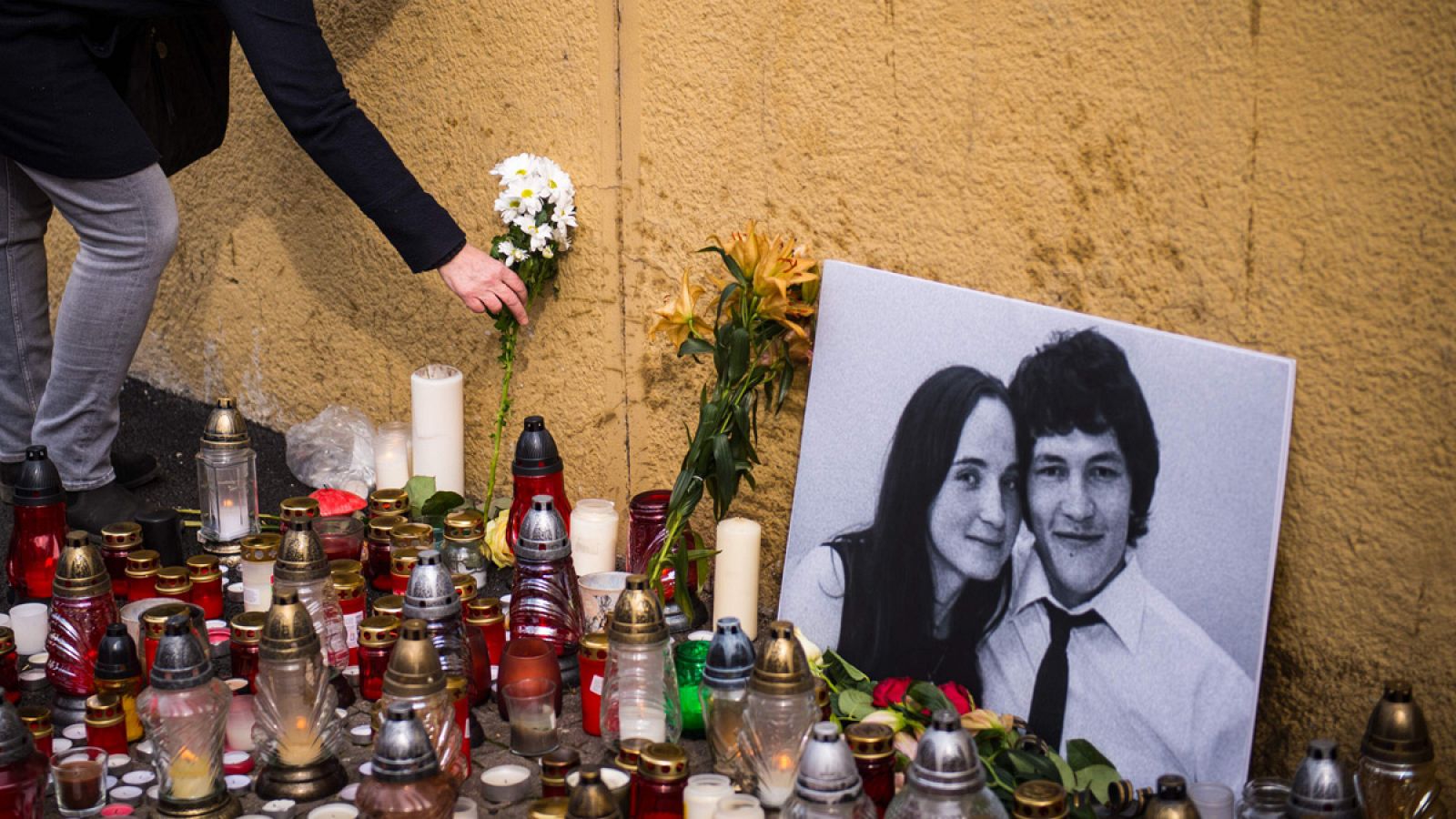 Una mujer coloca una vela junto a un retrato del periodista de investigación Jan Kuciak, asesinado junto a su novia en Bratislava