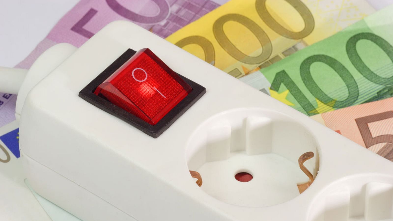 Una regleta de enchufes sobre varios billetes de euro