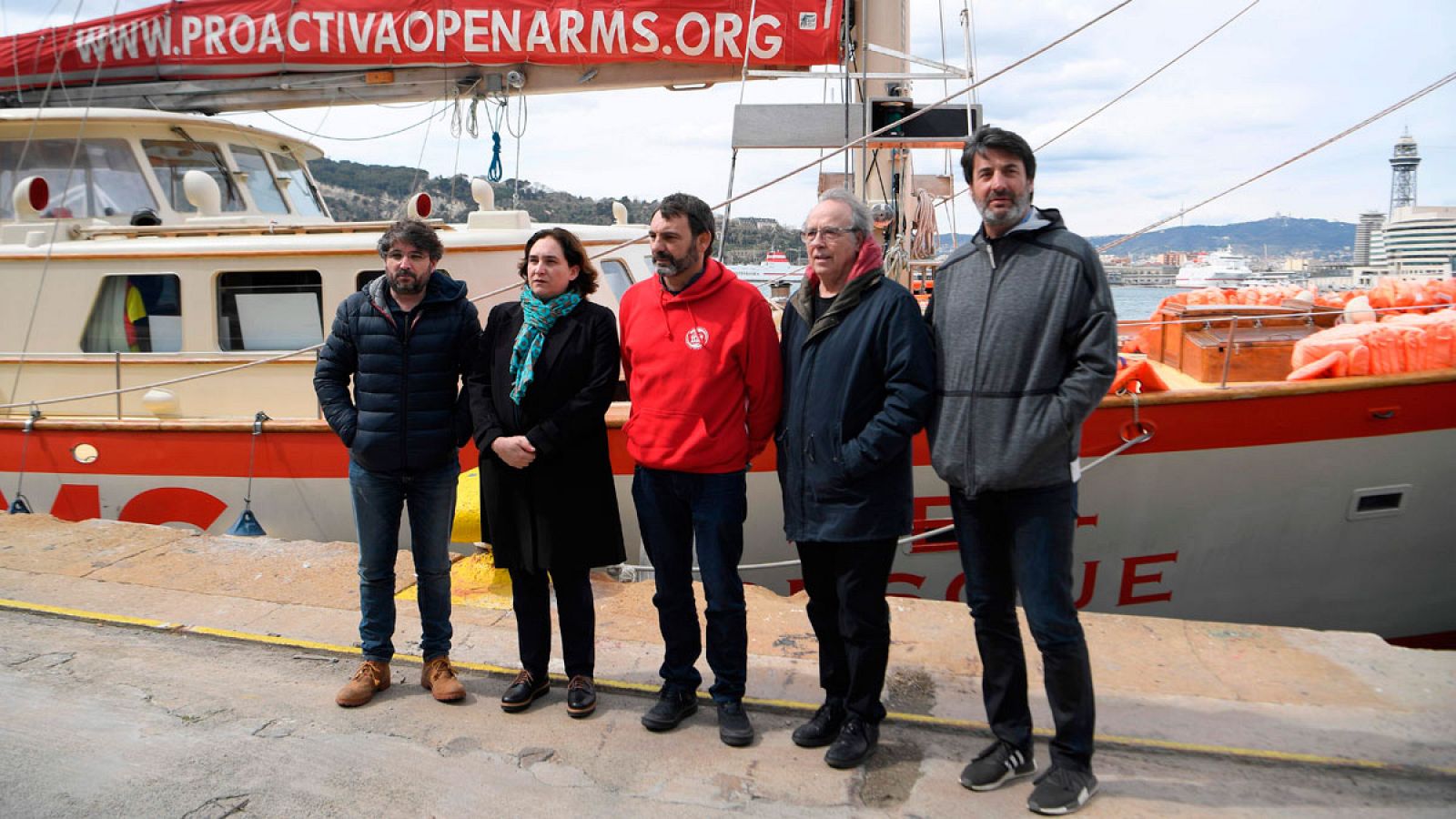 El fundador de la ONG Proactiva Open Arms, Òscar Camps, junto a la alcaldesa de Barcelona, Ada Colau, al cantante Joan Manuel Serrat, al periodista Jordi Évole y al exjugador de baloncesto Jordi Villacampa