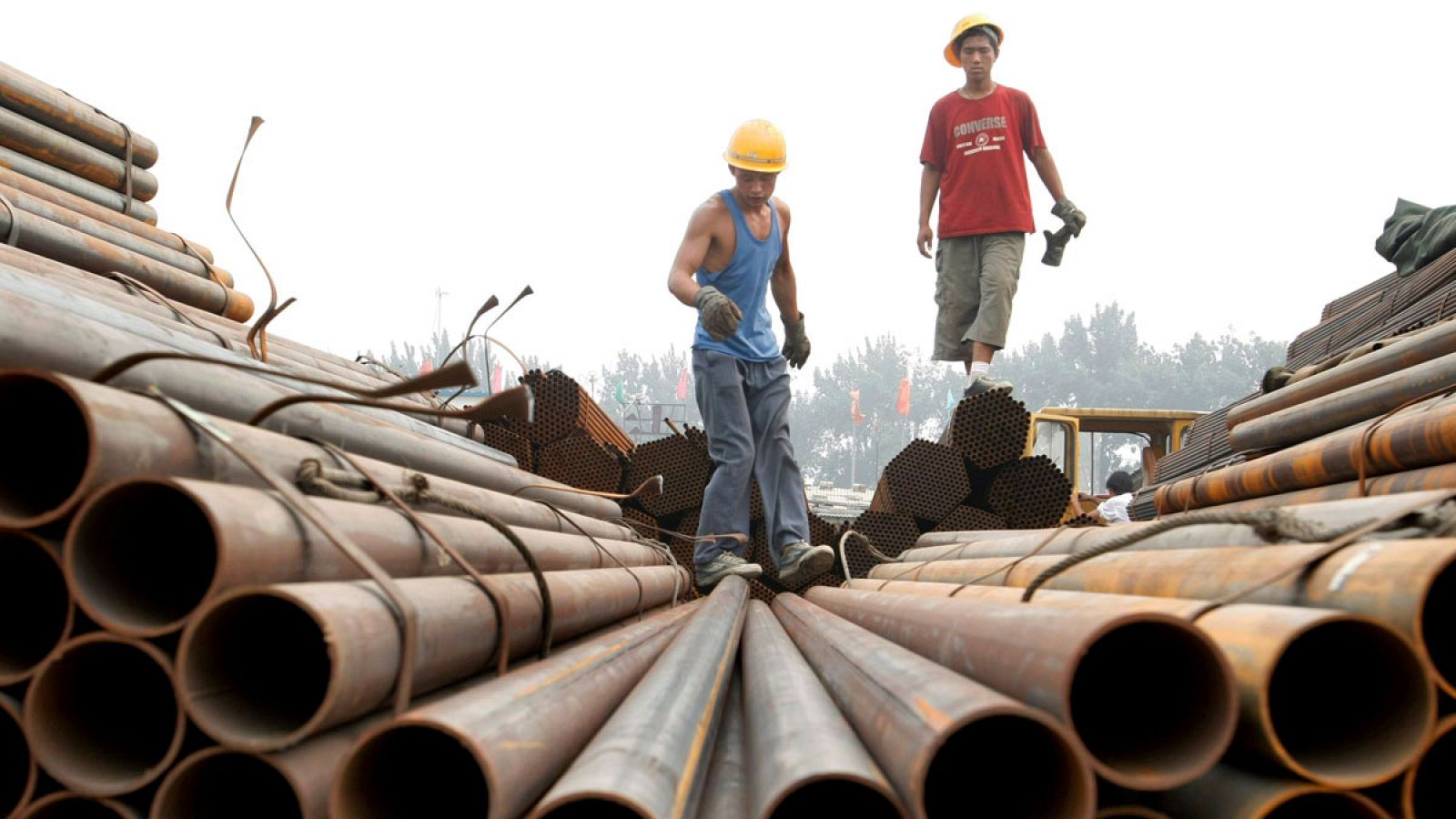 Fotografía de archivo del 27 de julio de 2007 que muestra unos operarios mientras transportan tuberías de acero para su pesaje en Pekín (China).