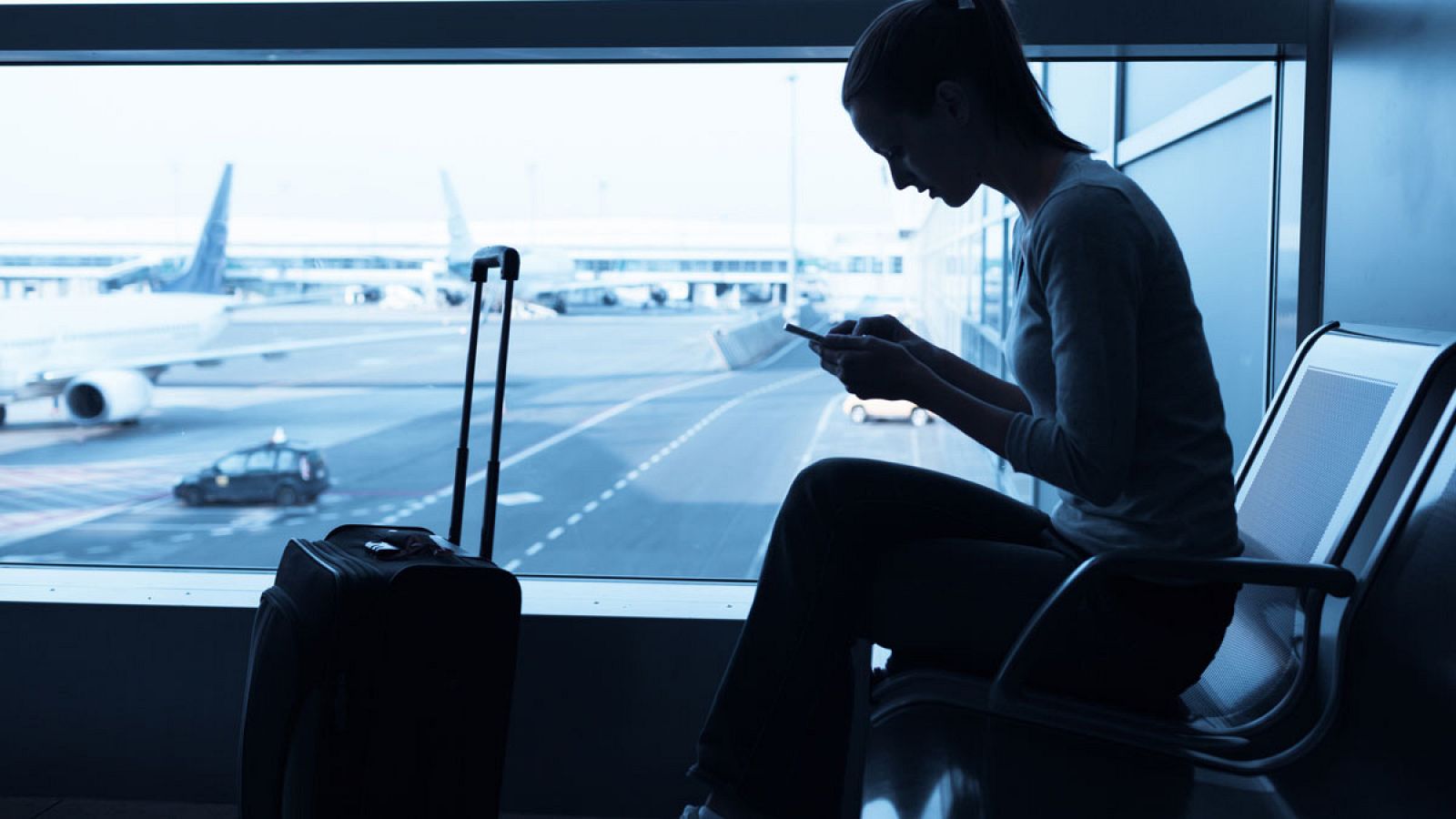 Una joven consulta su móvil mientras espera en un aeropuerto