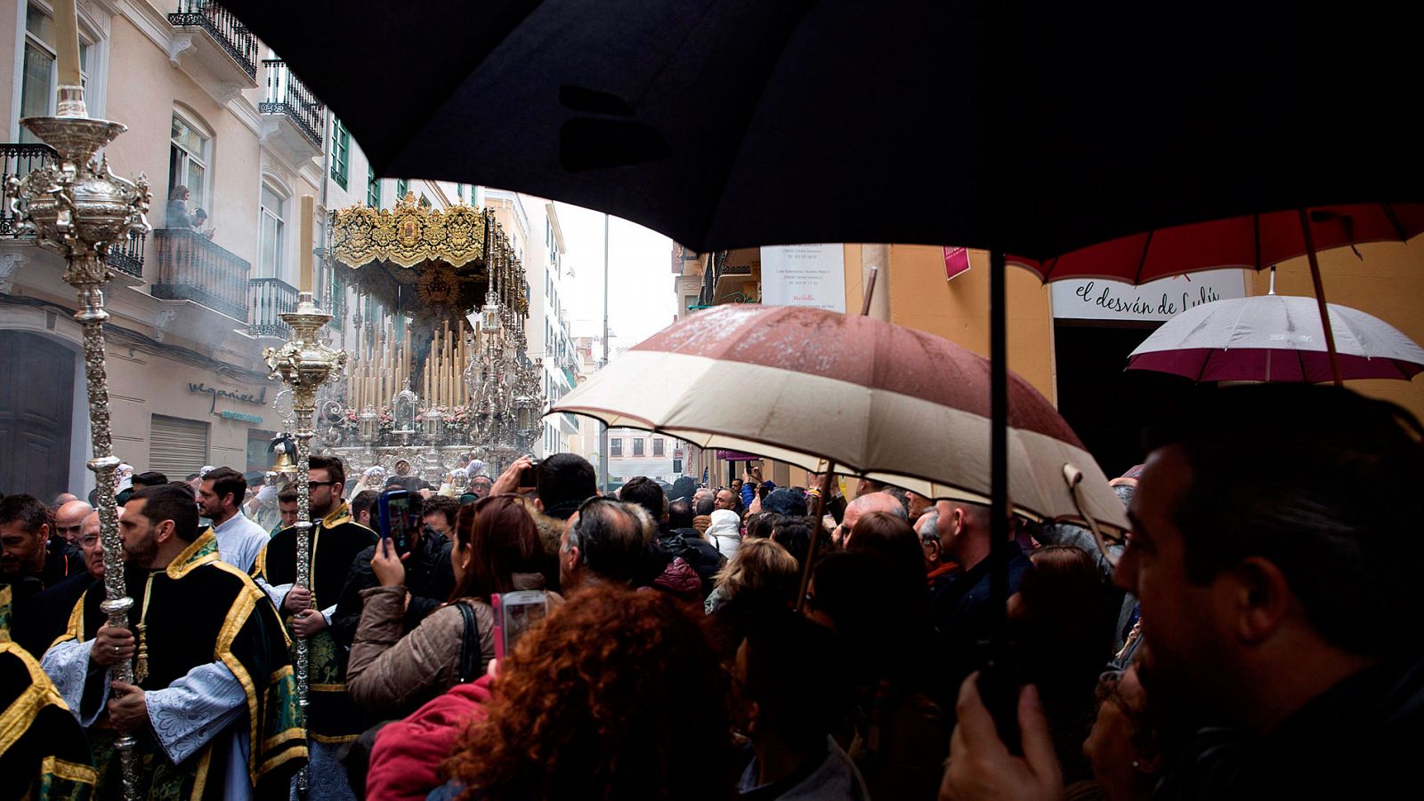 La gente ve bajo la lluvia una procesión de Semana Santa en Málaga el pasado Domingo de Ramos