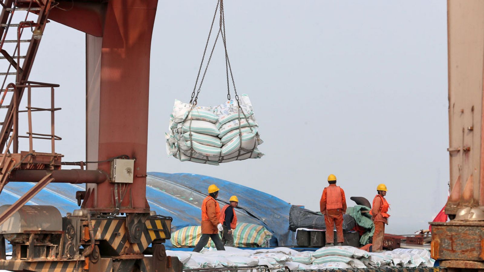 Operarios mientras transportan bolsas de habas de soja en un puerto en Nantong (China)