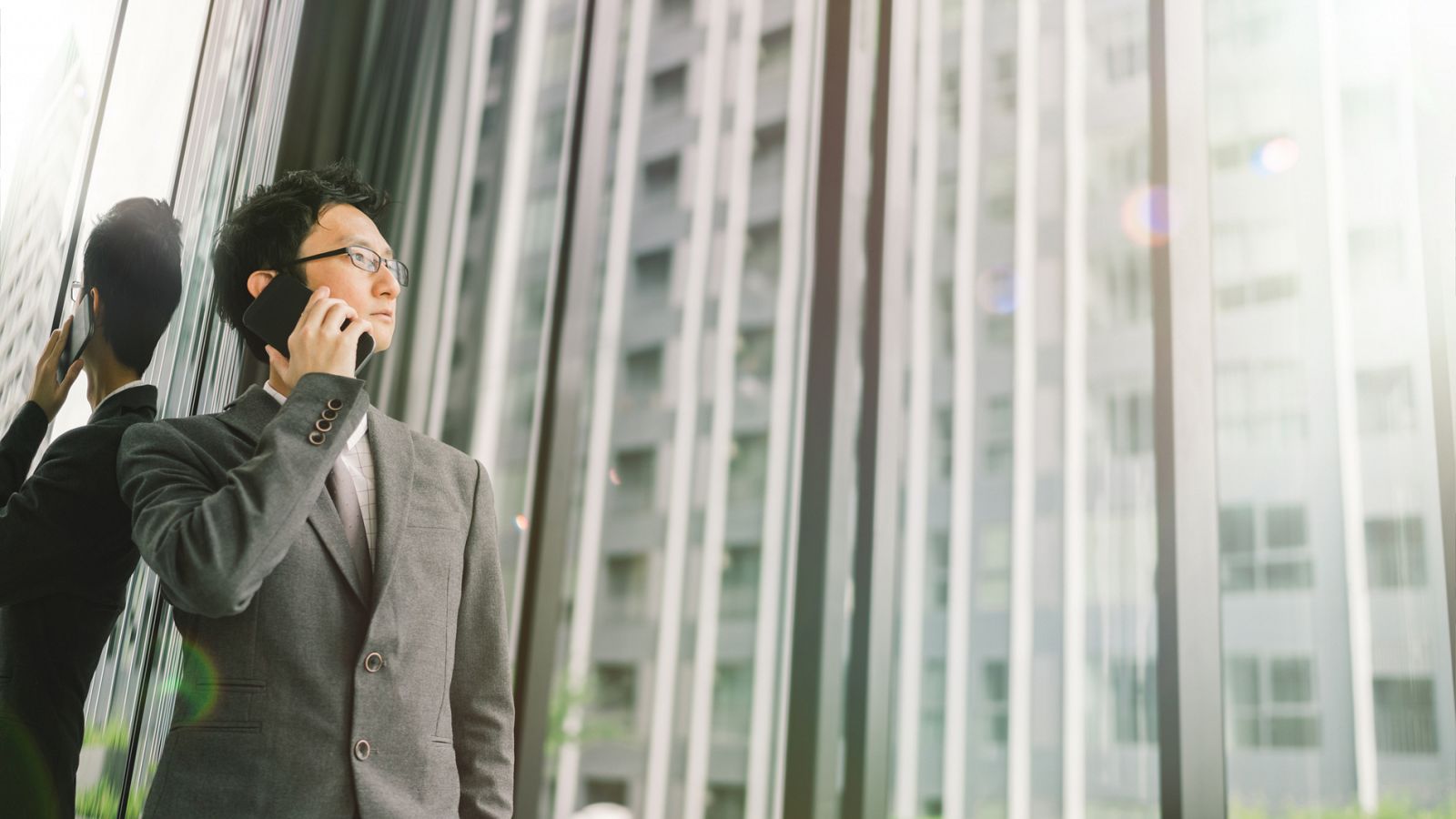 Un hombre de negocios asiático habla por el móvil desde un rascacielos