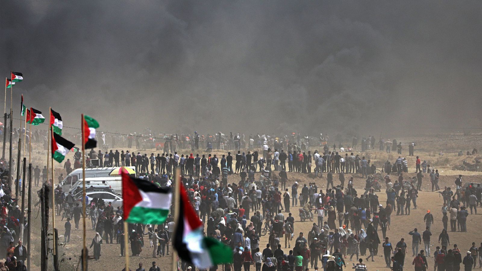 Una multitud camina entre la humareda generada por los neumáticos quemados durante las protestas en Gaza