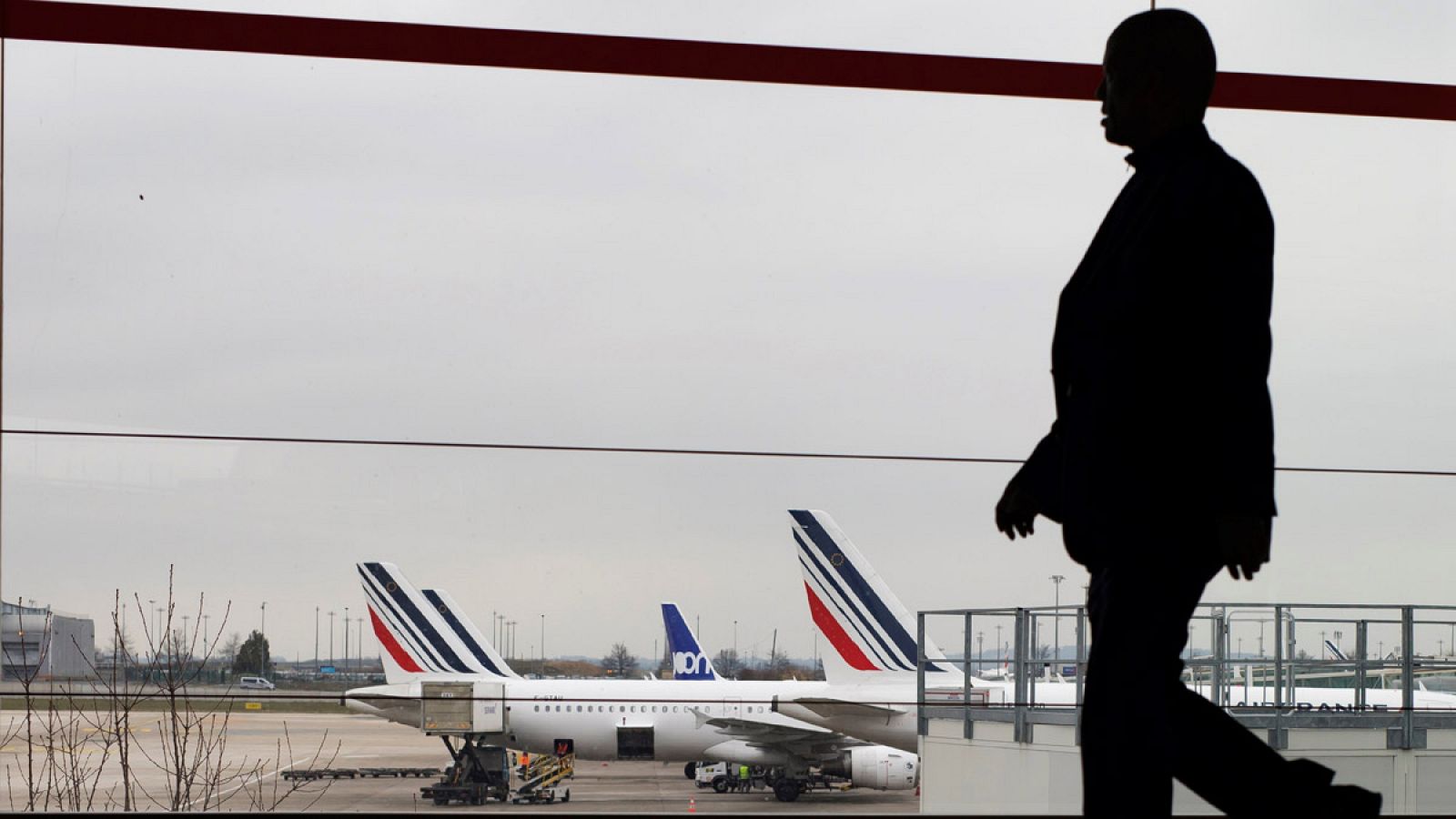 Un pasajero camina por una terminal del aeropuerto París-Charles de Gaulle, desde donde se observan varios aviones de la compañía Air France