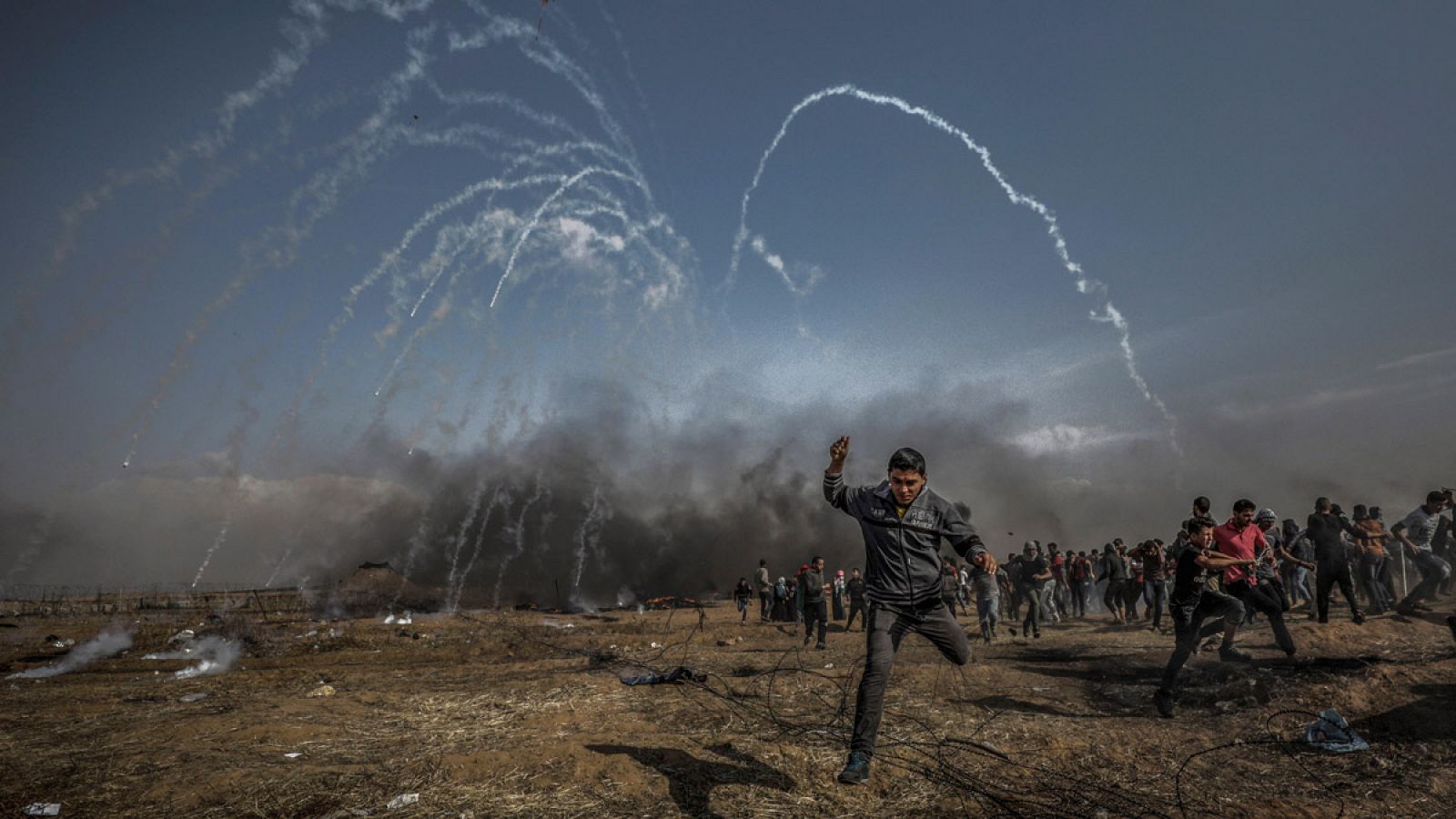 Manifestantes palestinos corren para refugiarse del gas lacrimógeno lanzado por soldados israelíes