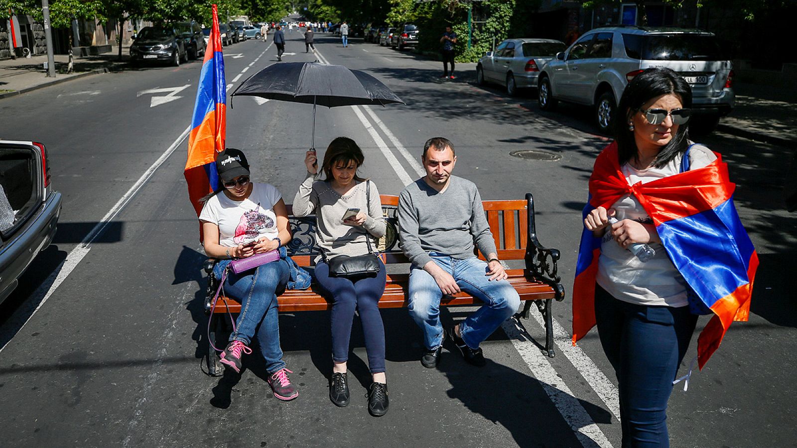 Partidarios del líder opositor Nikol Pashinián se sientan en un banco en Ereván para bloquear una carretera