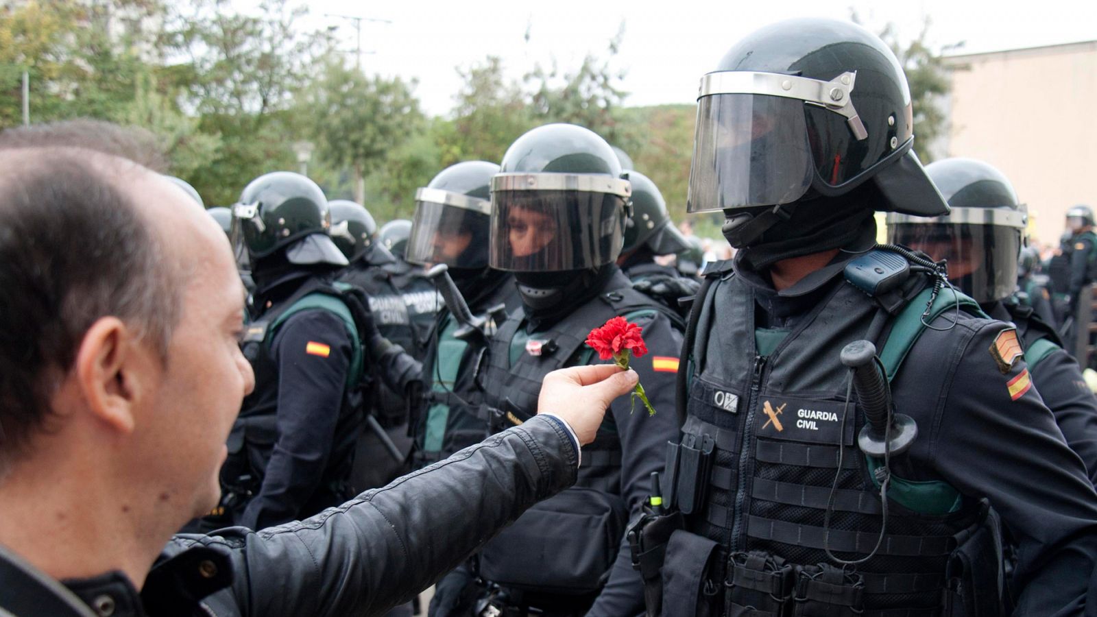 Un hombre ofrece un clavel a un agente de la Guardia Civil en  el centro Sant Julià de Ramis (Girona) durante el 1-O