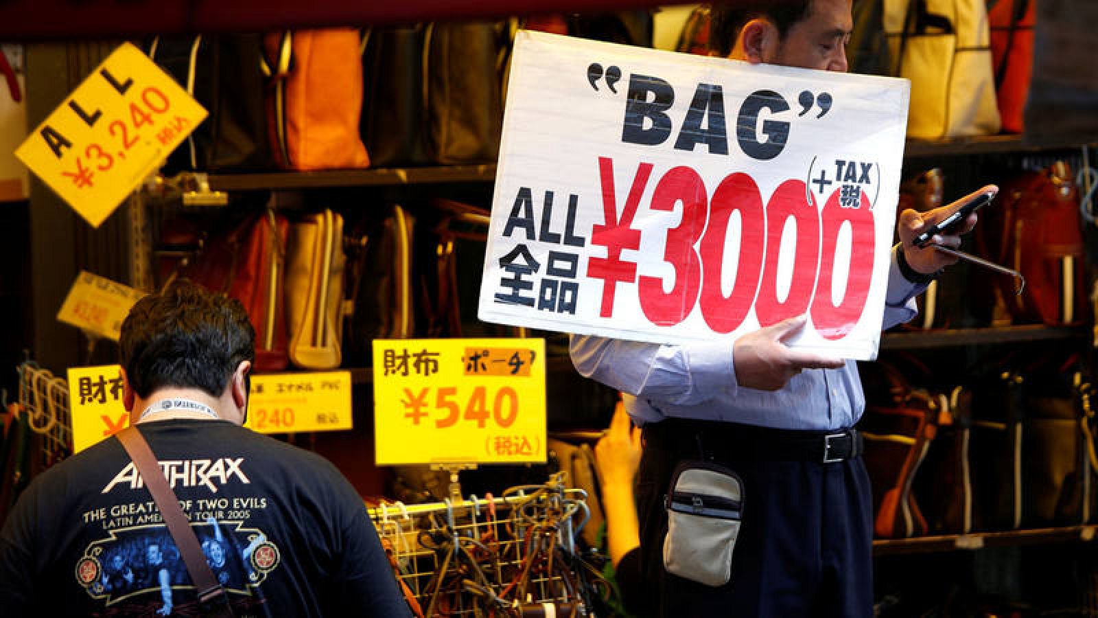 Un empleado de una tienda coloca un cartel de rebajas para tratar de atraer compradores