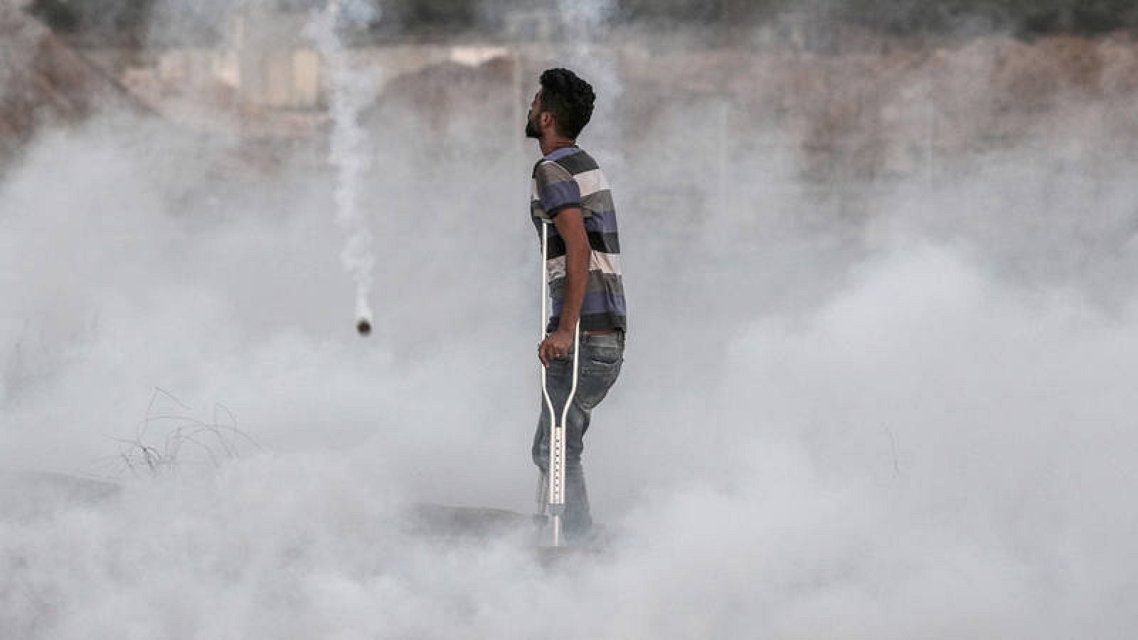 Un palestino herido entre los gases lacrimógenos lanzados por el Ejército israelí en la frontera con Gaza