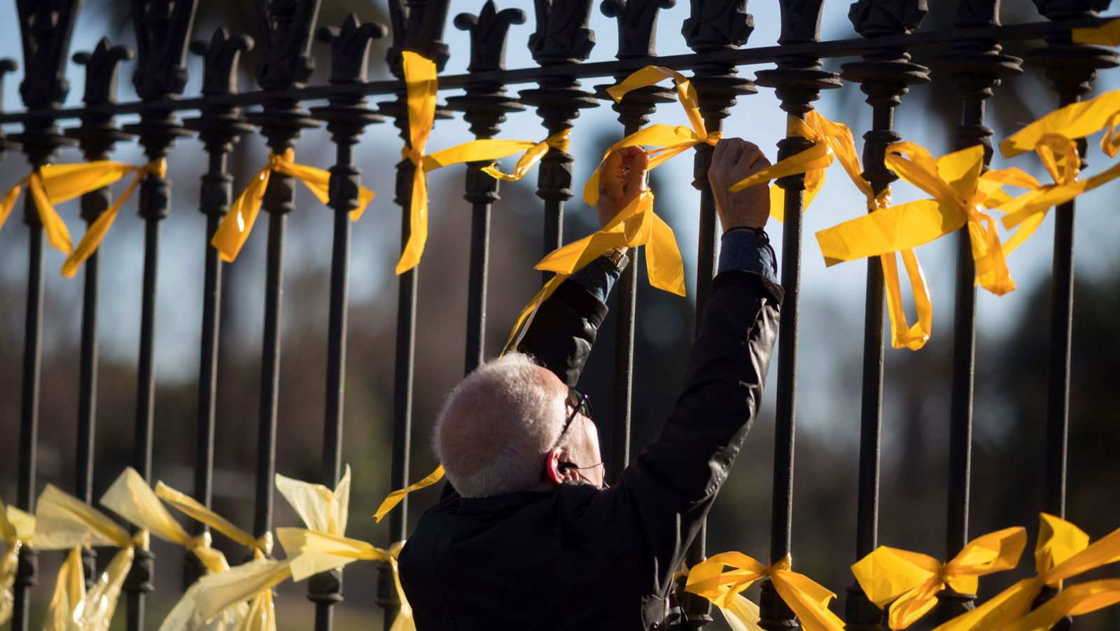 Imagen de archivo de un hombre colocando lazos amarillos en la verja del Parque Ciutadella de Barcelona