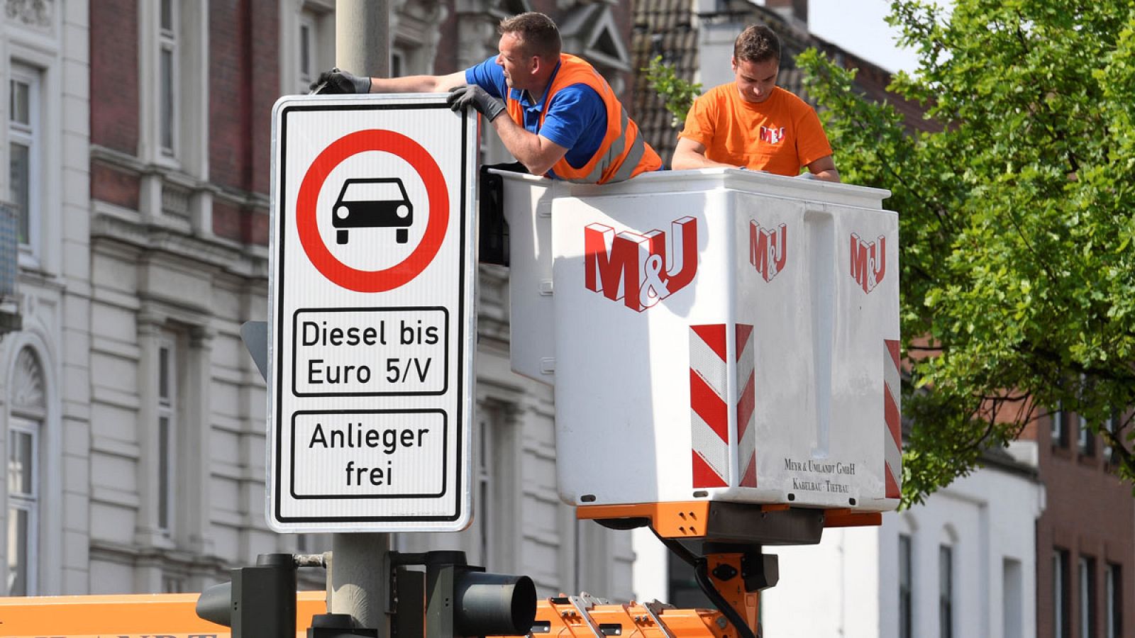 Varios operarios instalan señales de tráfico que indican la prohibición para vehículos diésel contaminantes