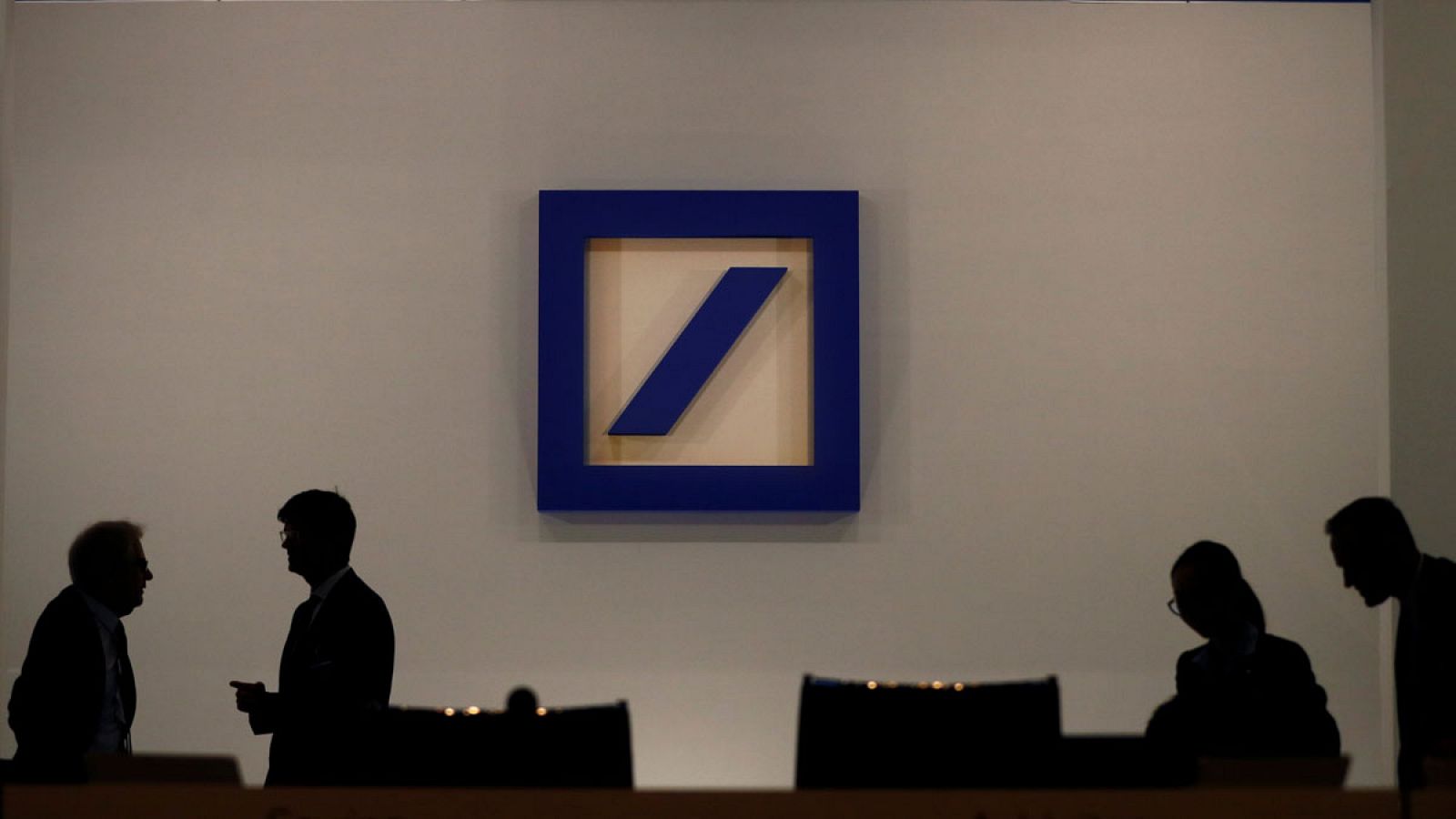 Siluetas de varios empleados del Deutsche Bank perfiladas sobre un fondo con el logo de la entidad