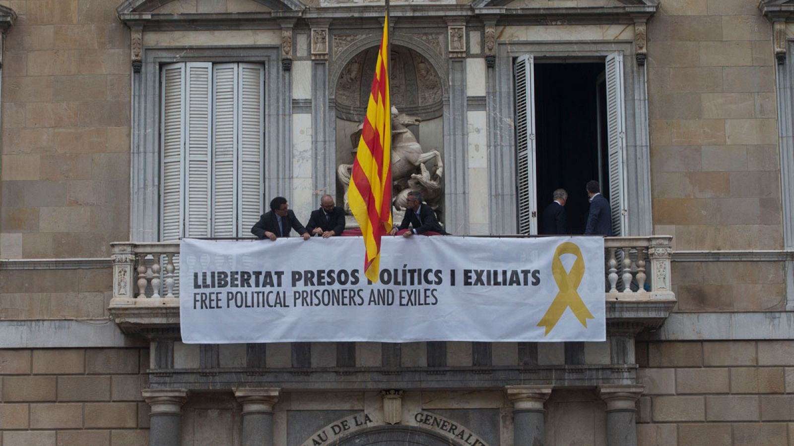 Trabajadores de la Generalitat colocan en el balcon del Palau una pancarta por los "políticos presos y exiliados"