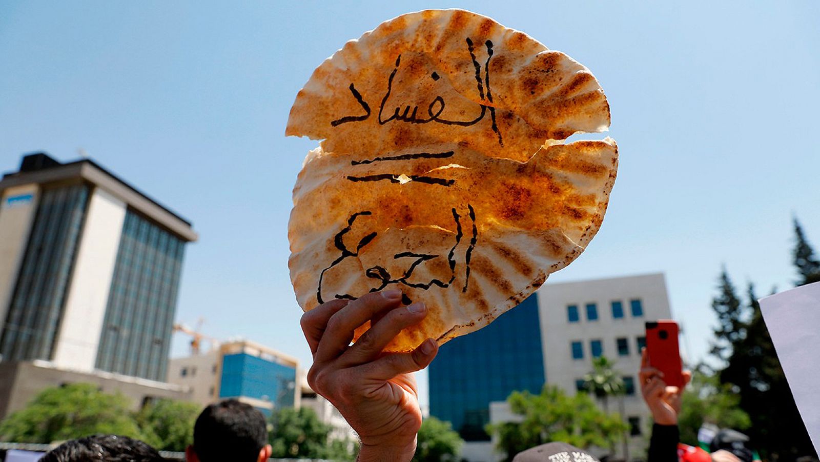 Un manifestante sostiene una pieza de pan con la frase en árabe "Corrupción = Hambre", durante una protesta en Amman