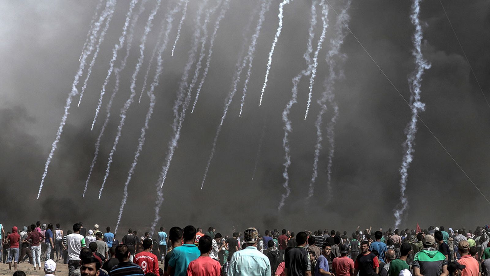 Manifestantes palestinos observan el impacto de gas lacrimógeno israelí en Gaza