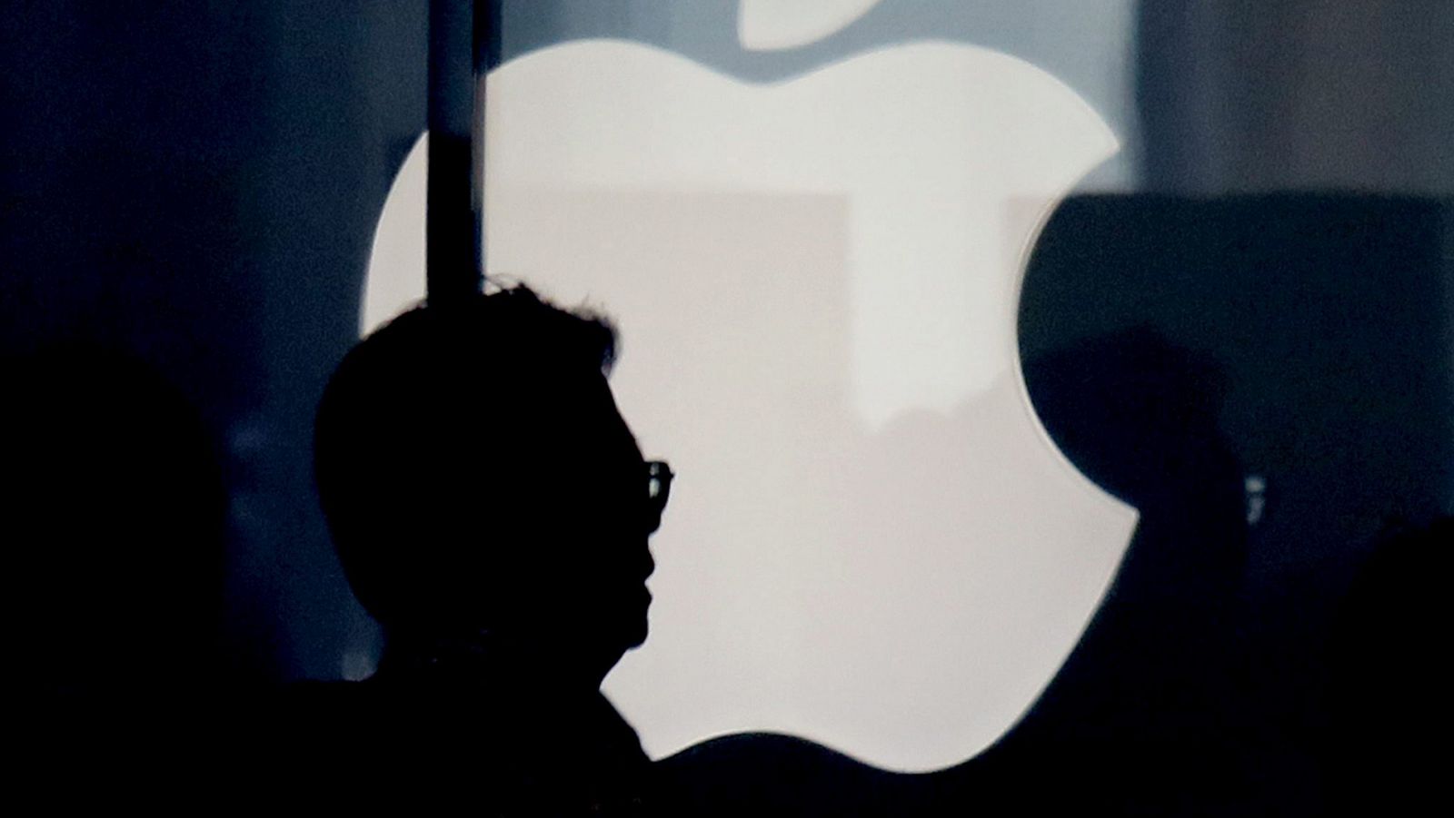 Silueta de un hombre frente a un logotipo de Apple en una tienda en Tokio