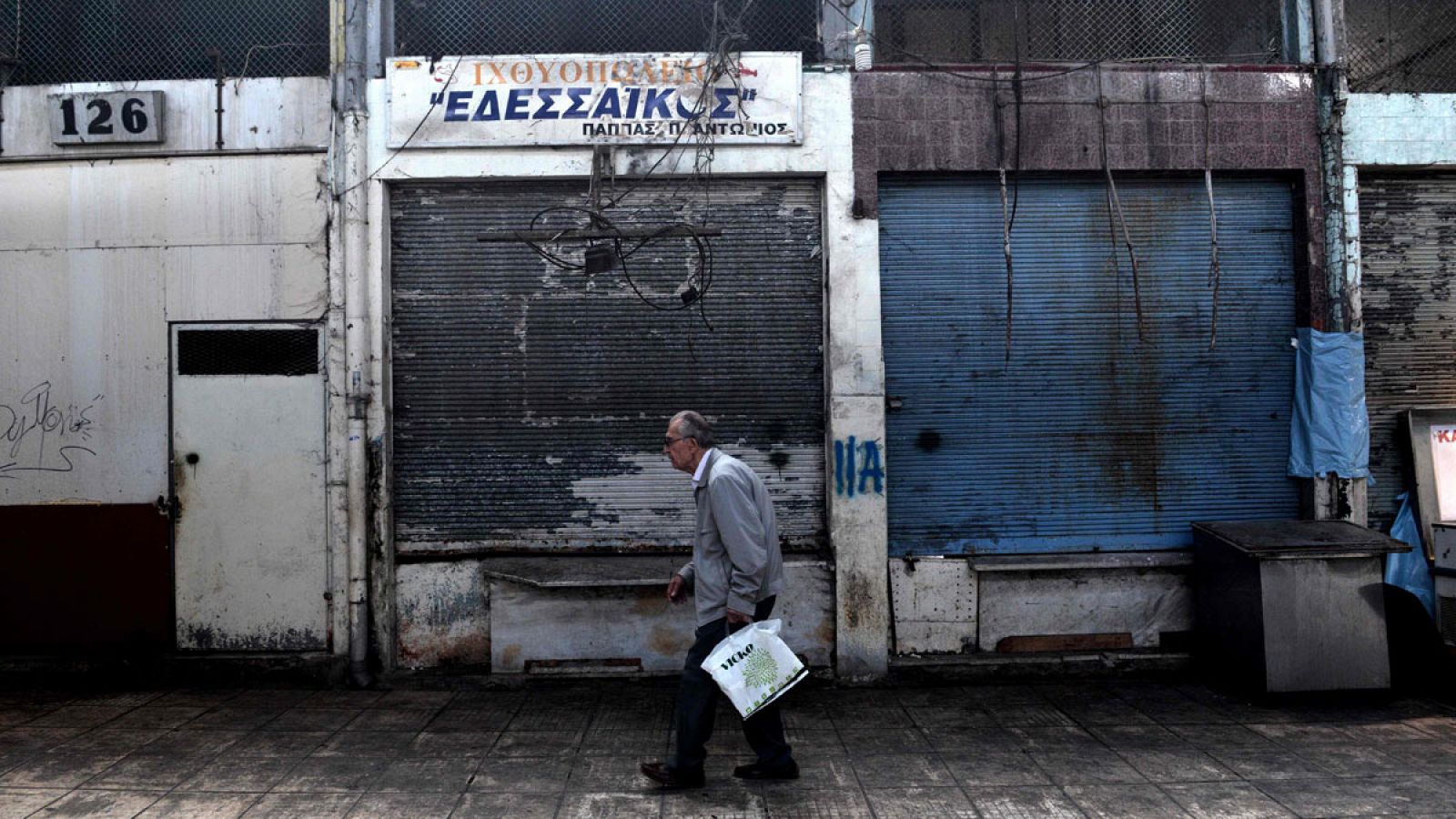 Un hombre pasa delante de varios comercios cerrados en el centro de Salónica