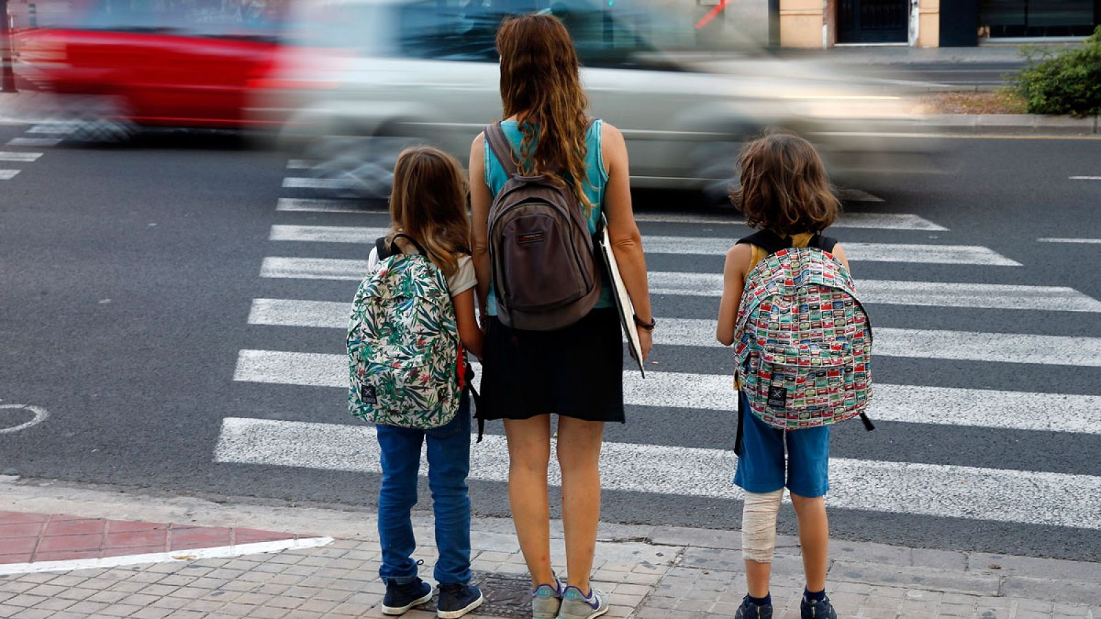 Dos niños, acompañados de su madre, se dirigen al colegio en Valencia