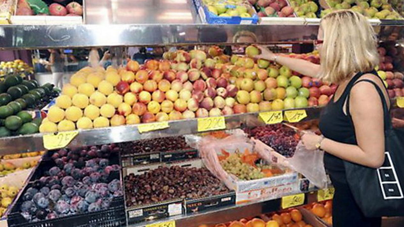 Una mujer selecciona fruta en un puesto del mercado