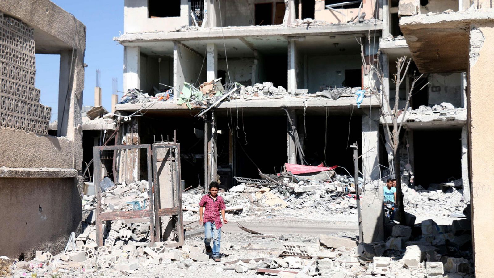 Un niño sirio camina entre edificios destruídos durante los ataques aéreos en la ciudad de Nawa