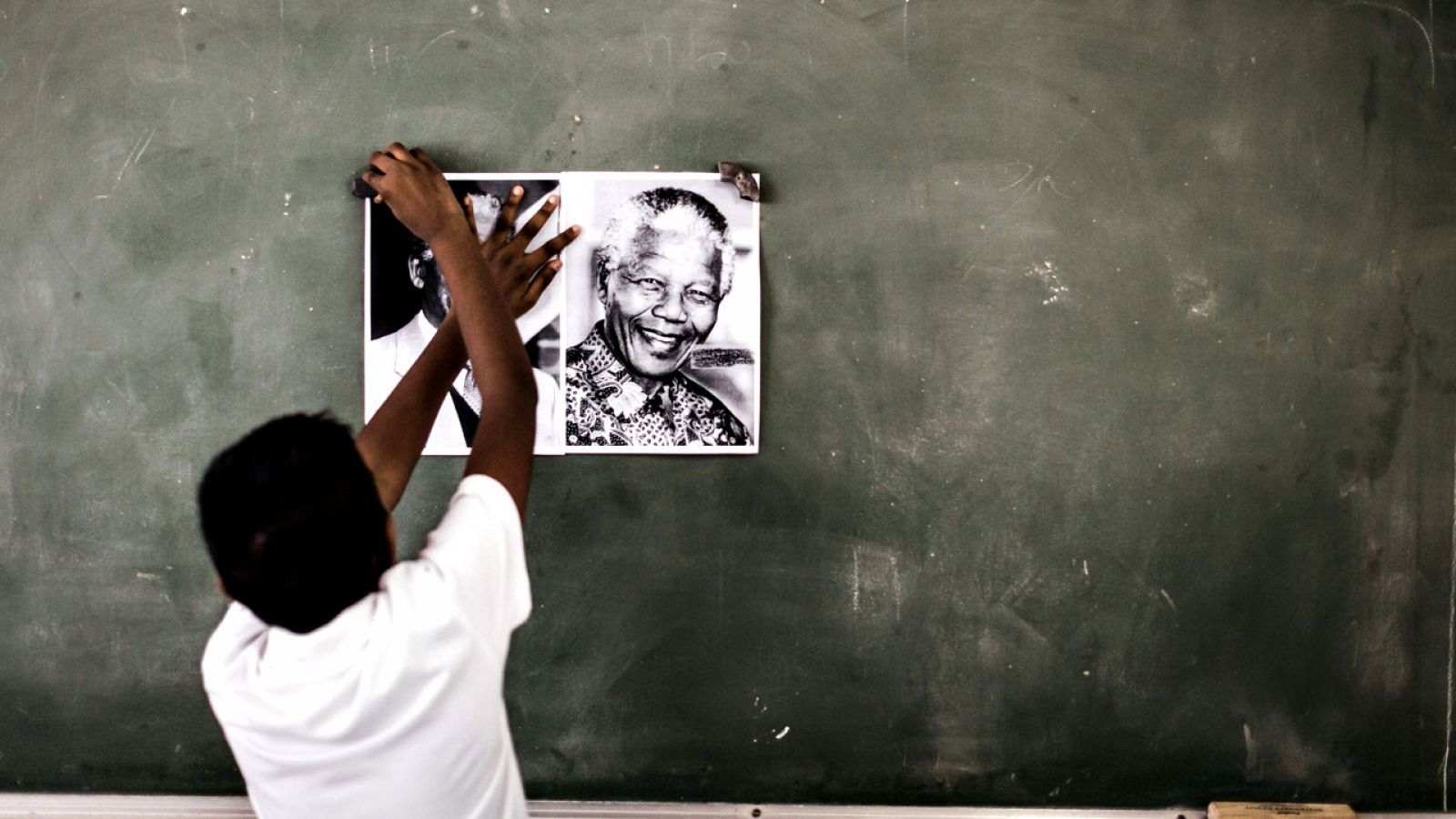 Un escolar cuelga un retrato de Nelson Mandela en la pizarra de su colegio, en Durban