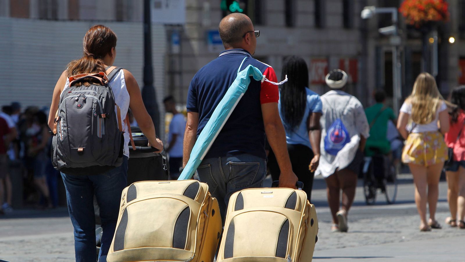 Dos turistas caminan por el centro de madrid con sus maletas