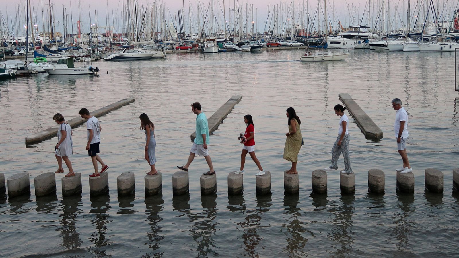 Unos turistas cruzan la marina del puerto de Palma de Mallorca