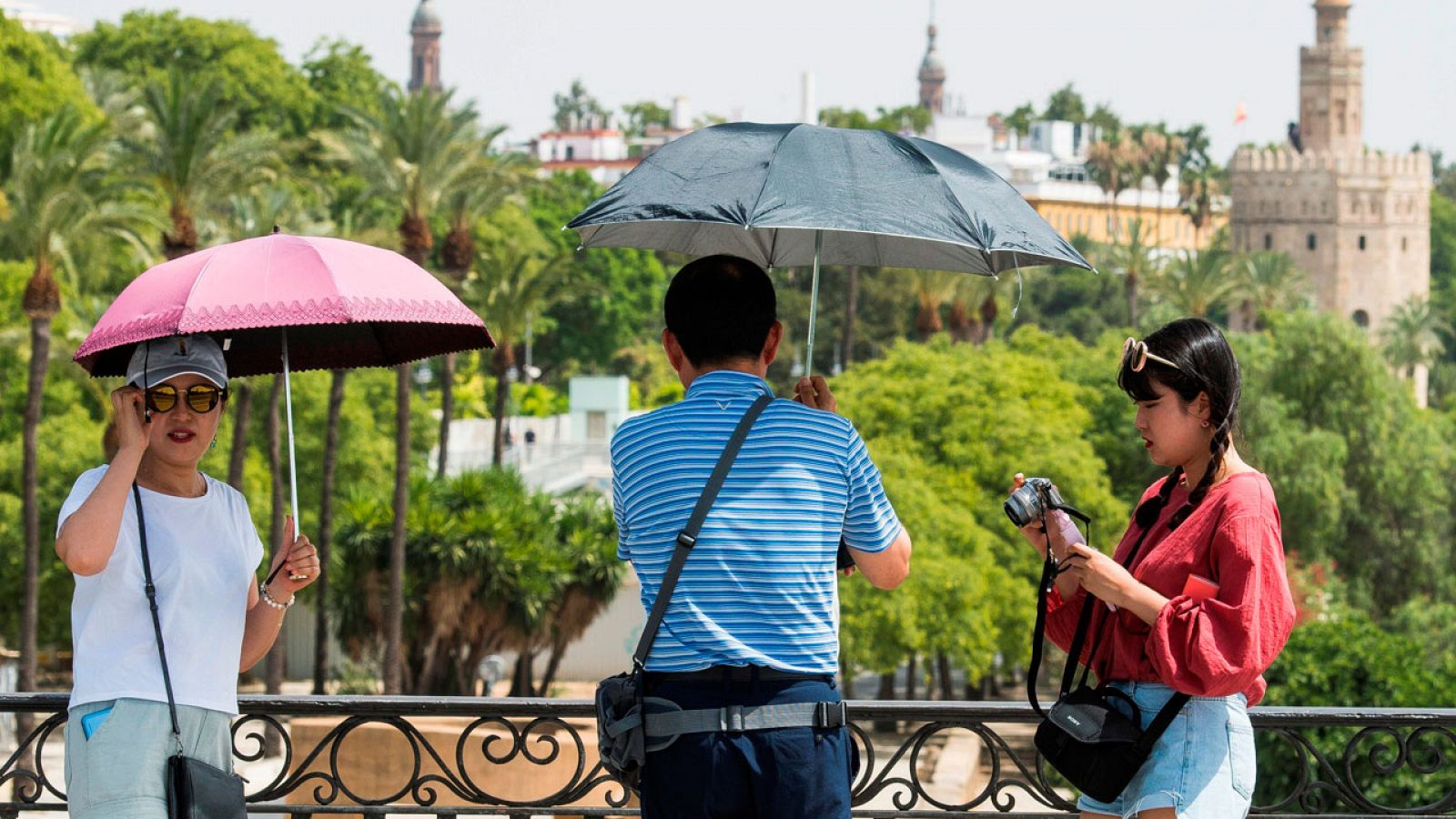 Turistas se protegen del sol por el intenso calor.