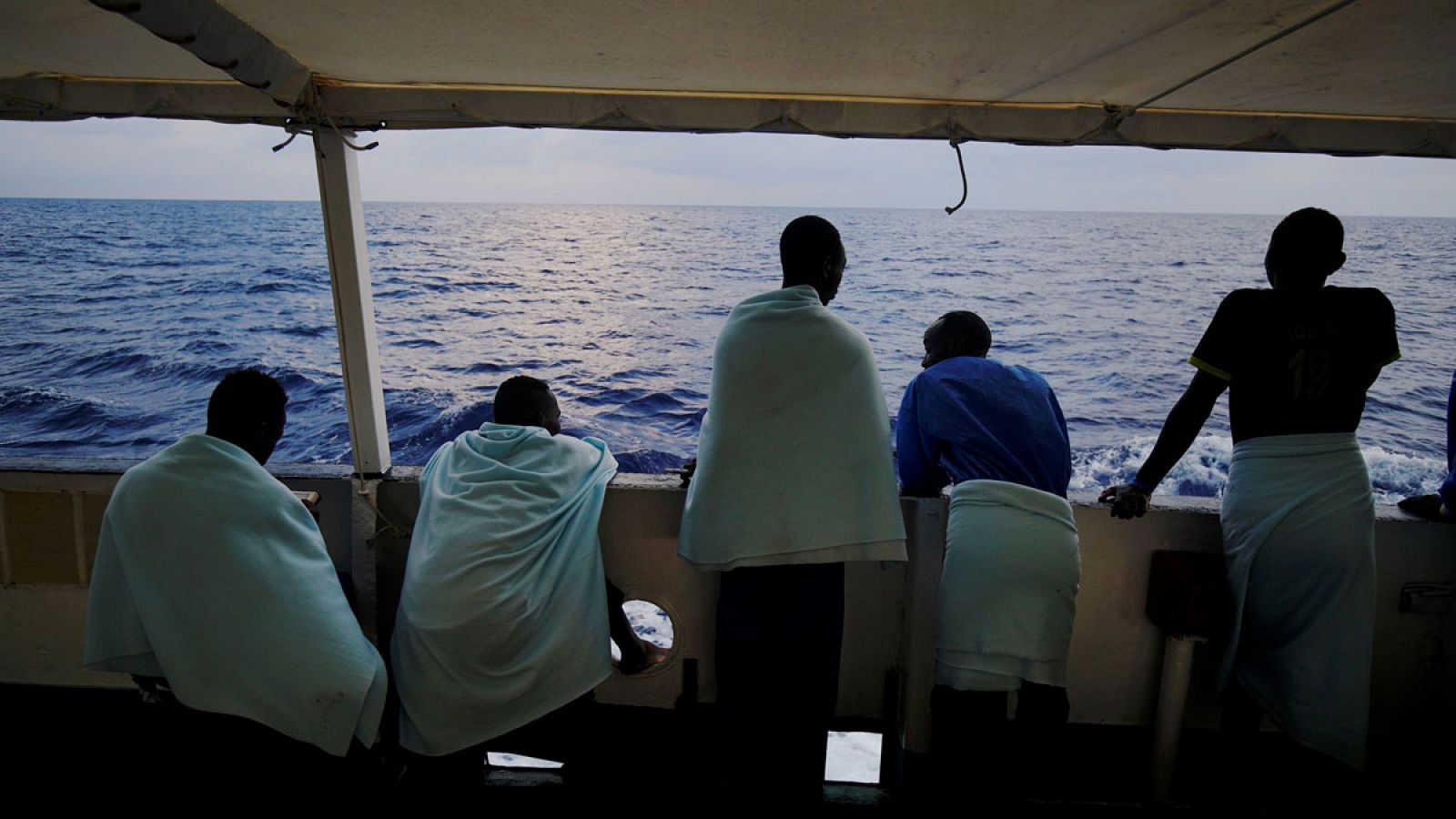 Cinco migrantes observan el Mediterráneo desde el barco de la ONG Proactiva Open Arms.