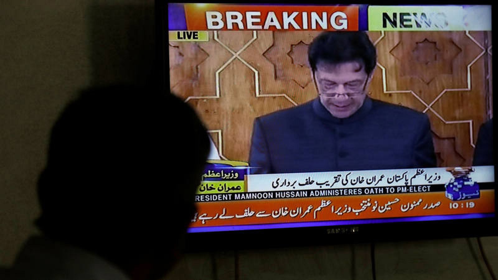 Un hombre mira el discurso de Imran Khan durante su toma de posesión como primer ministro de Pakistán