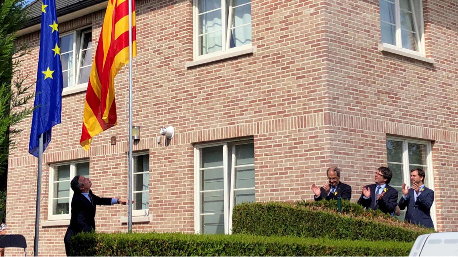 Torra, Puigdemont y Toni Comín aplauden el izado de bandera en la casa de Waterloo