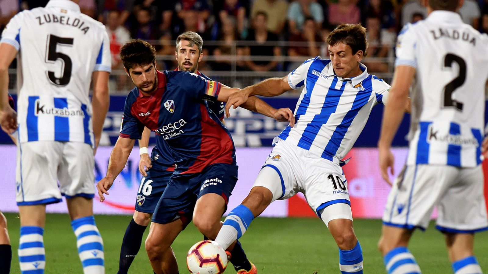 El centrocampista del Huesca Gonzalo Melero (c-i) pelea un balón con el delantero de la Real Sociedad, Mikel Oyarzabal (c-d).