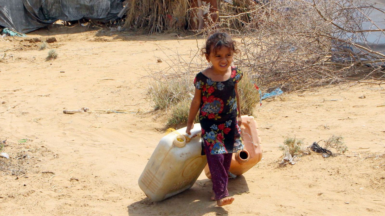 Una niña yemení cargando con unos bidones de agua.