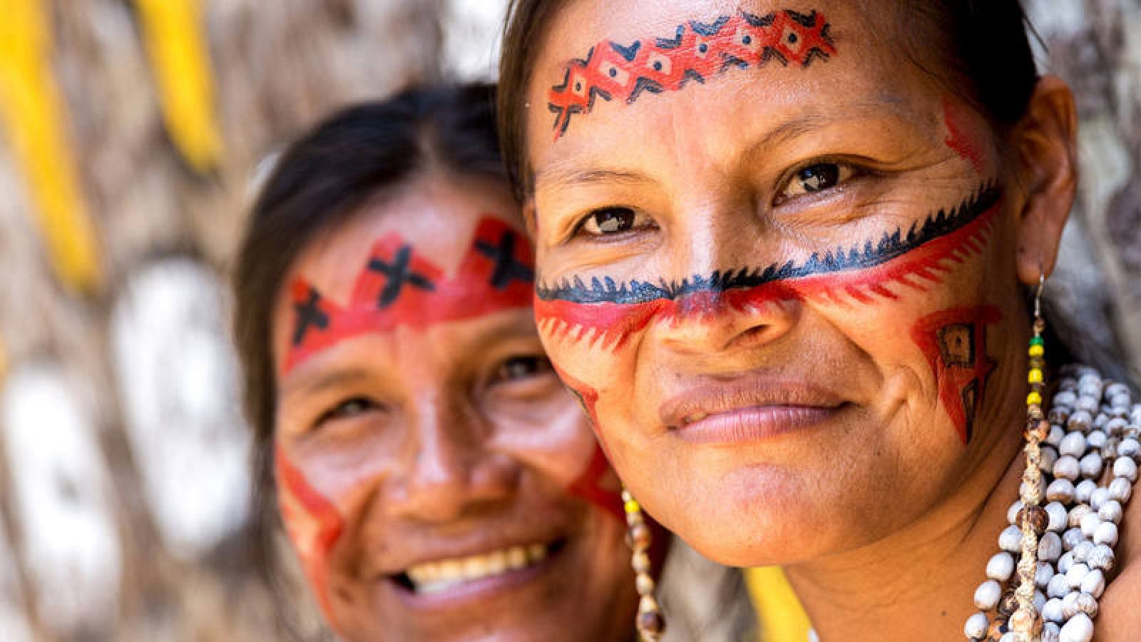  Dos mujeres indígenas sonríen con la cara pintada al modo tradicional.