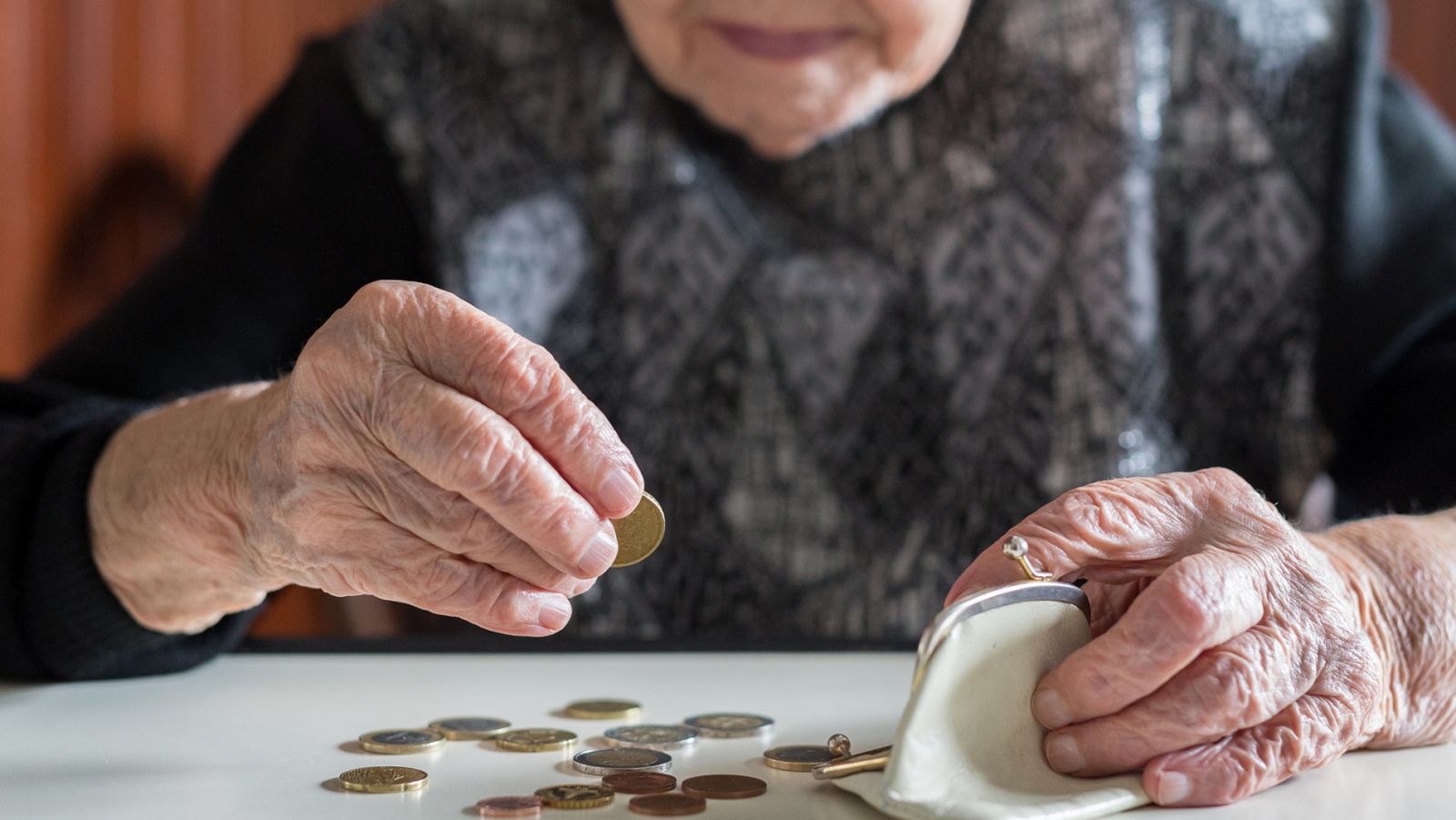 Una mujer mayor cuenta las monedas de su monedero
