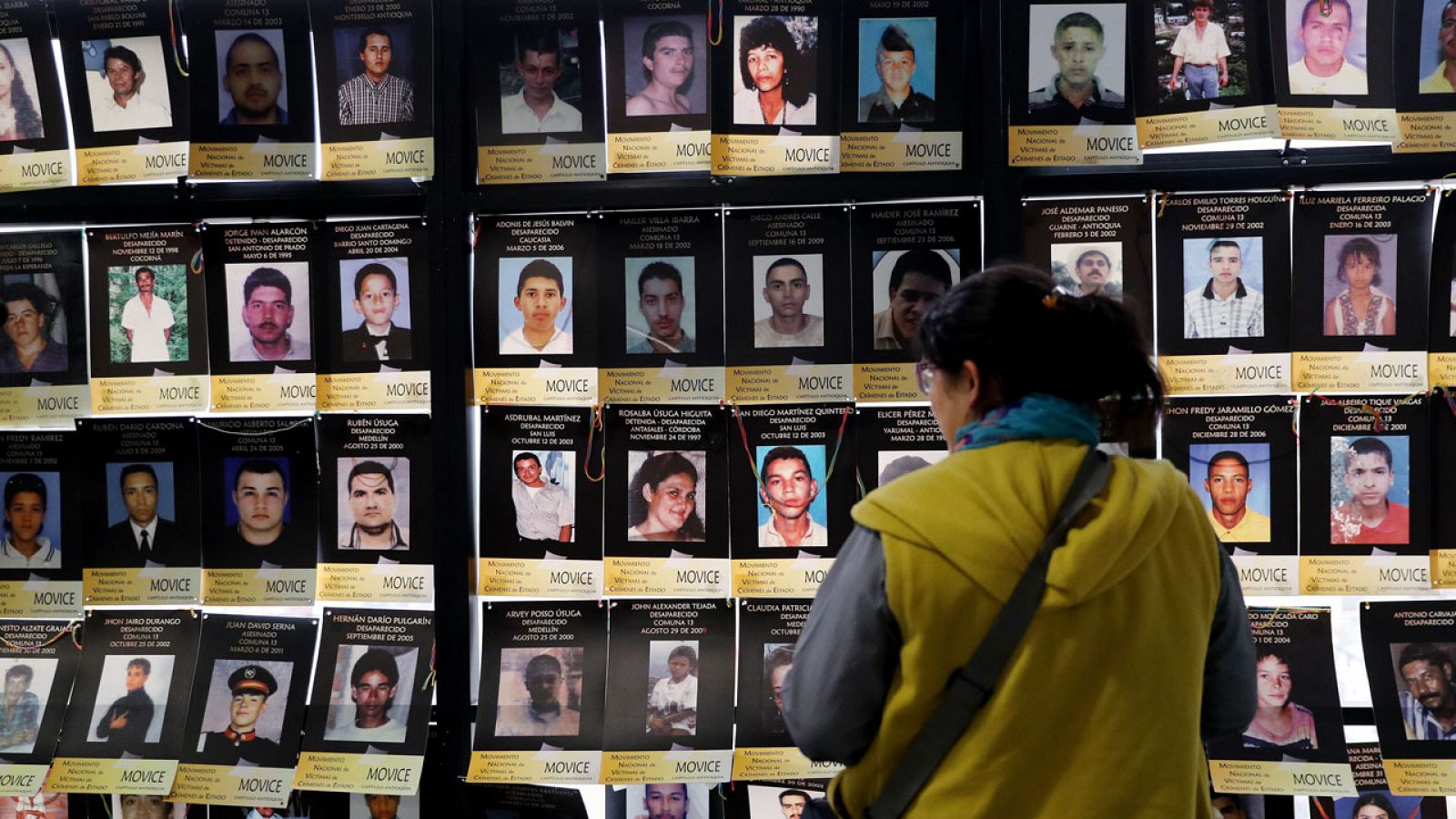 Una mujer observa los retratos de víctimas de crímenes de Estado en Bogotá